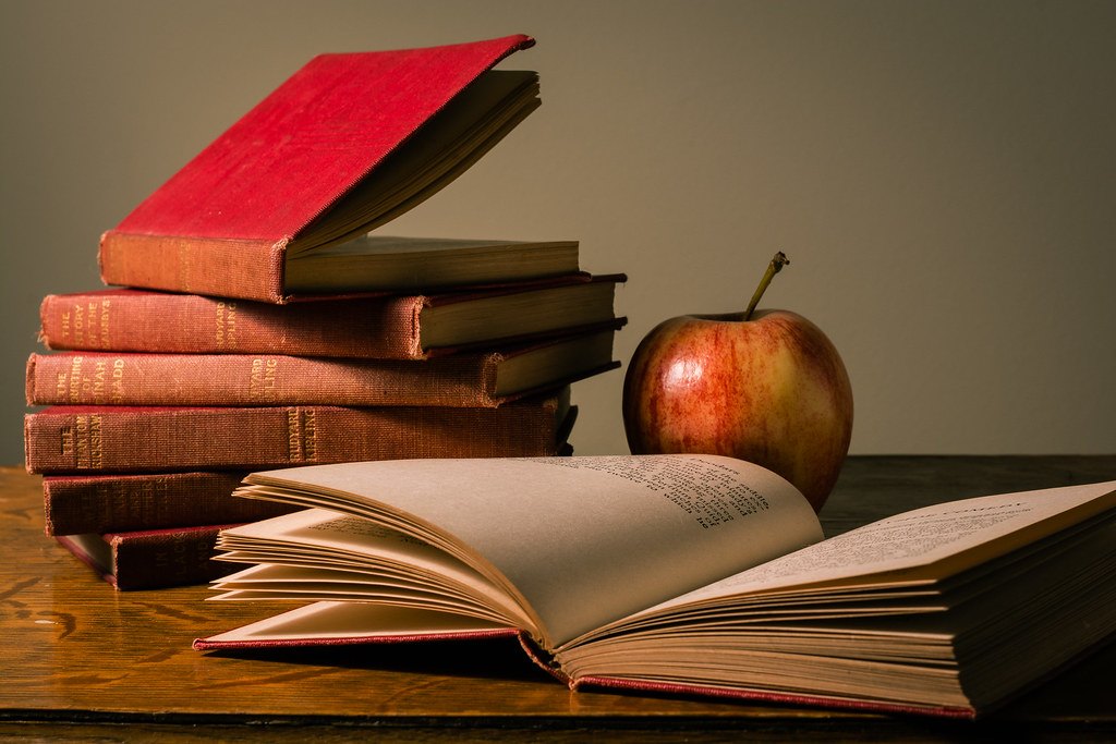 Pile de livres et pomme illustrant la révision du français et de la littérature pour le brevet